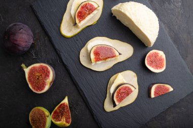 Armut, süzme peynir, incir ve ballı yaz aperatifleri siyah beton arka planda. Üst manzara, düz yatak, yakın çekim..