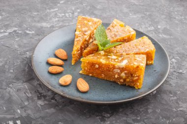 Geleneksel Türk şekerleri karamelli kavun, kavrulmuş ceviz, fındık, şam fıstığı ve mavi seramik tabakta siyah betondan yapılmış. Yan görünüm, düz görünüm, yakın çekim.