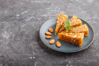 Geleneksel Türk şekerleri karamelli kavun, kavrulmuş ceviz, fındık, şam fıstığı ve mavi seramik tabakta siyah betondan yapılmış. kenar görünümü, düz görünüm, kopyalama alanı.