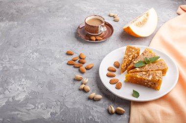 Geleneksel Türk şekerleri karamelli kavun, kavrulmuş ceviz, fındık, kaju, beyaz seramik tabakta şam fıstığı ve gri beton zemin üzerinde bir fincan kahveden yapılır. Yan görünüm, boşluk kopyala.