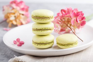 Beyaz seramik tabakta yeşil badem kurabiyeleri ve gri beton arka plan ve keten tekstil. Yan görünüm, yakın görünüm, seçici odak.