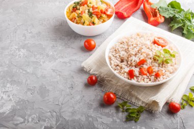 Cilalanmamış pirinç lapası haşlanmış sebzeler ve gri beton arka planda keklik otu ve keten tekstil. Yan görünüm, kapat, boşluğu kopyala.