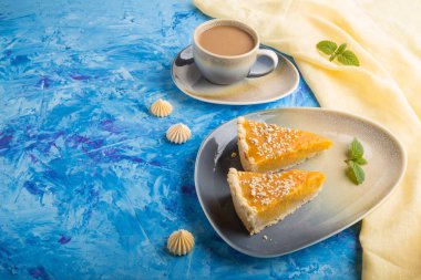 İki adet geleneksel Amerikan balkabağı turtası mavi beton arka planda bir fincan kahve ve sarı tekstil. yan görünüm, boşluk kopyala, karşıtlık.