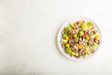 Romanesco lahanasından vejetaryen salata, şampiyonlar, kızılcık, avokado ve balkabağı beyaz ahşap arka plan ve keten tekstil. Üst görünüm, kopyala boşluk, düz uzanma.