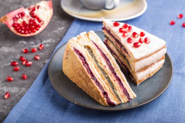 Nar reçelli ev yapımı kek ve siyah beton arka planda bir fincan kahve ve mavi tekstil. Yan görünüm, yakın görünüm, seçici odak.