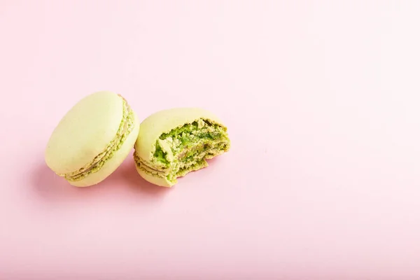 Ganze Und Gebissene Grüne Macarons Oder Makronenkuchen Auf Pastellrosa Hintergrund — Stockfoto