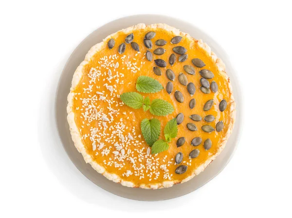 Traditional american sweet pumpkin pie decorated with mint, sesame and pumpkin seeds isolated onwhite background. top view, close up, flat lay.