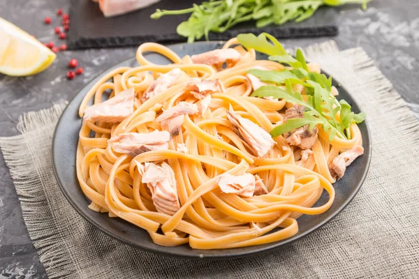 Somon ve somon biftekli Semolina makarnası. Siyah beton arka plan ve keten tekstil. Yan görünüm, yakın görünüm, seçici odak.