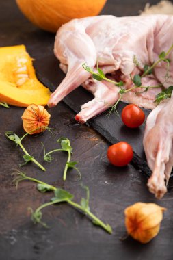 Balkabaklı, domatesli tam çiğ tavşan, siyah beton arka planda bezelye filizi ve keten tekstil. Yan görünüm, yakın görünüm, seçici odak.