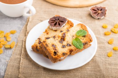 Kuru üzümlü ev yapımı kek, kurutulmuş hurma ve gri beton arka planda bir fincan sıcak çikolata ve keten tekstil. Yan görünüm, yakın görünüm, seçici odak.