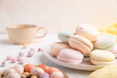 Renkli zephyr veya bir fincan kahveli marşmelov ve beyaz beton arka plan ve sarı tekstil üzerine sürükleyici. Yan görünüm, yakın görünüm, seçici odak.