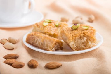 Geleneksel Arap tatlıları (basbus, kunafa, baklava) ve gri beton arka plan ve turuncu tekstil üzerinde bir fincan kahve. Yan görünüm, yakın görünüm, seçici odak, makro.