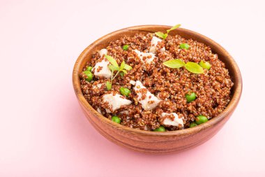 Yeşil bezelyeli kinoa lapası ve pastel pembe arka planda ahşap kasede tavuk. Yan görünüm, kapat.