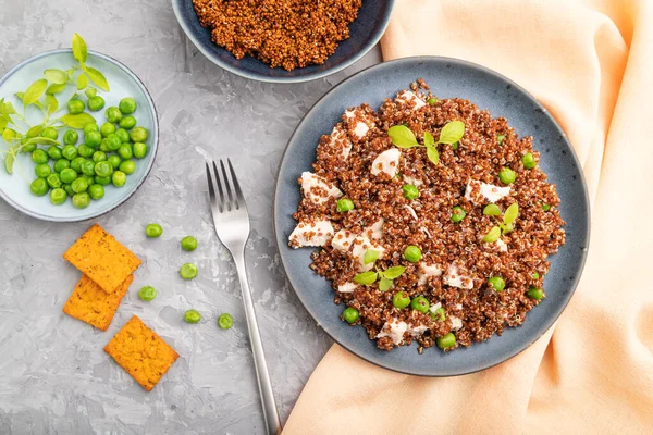 Yeşil bezelyeli kinoa lapası ve gri beton arka planda seramik tabakta tavuk ve turuncu tekstil. Üst manzara, düz yatak, yakın çekim..