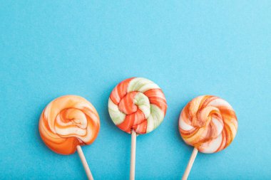 Mavi pastel arka planda üç lolipop şekeri. Boşluğu kopyala, üst görünüm, düz uzanma.