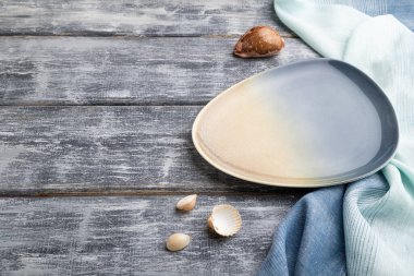 Gri ahşap arka planda boş mavi seramik tabak ve mavi tekstil. Yan görünüm, boşluk kopyala.