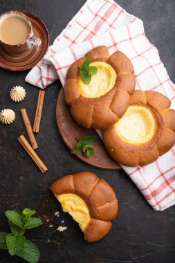 Siyah beton arka planda bir fincan kahve ve keten tekstil ile ekşi kremalı çörek. Üst görünüm, düz görünüm, yakın çekim.