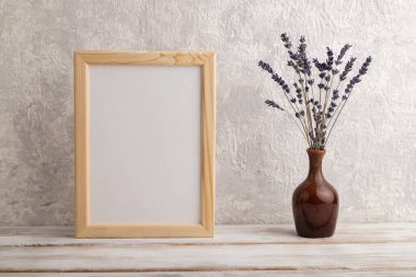 Beyaz ahşap çerçeve, gri beton arka planda seramik vazoda lavanta renginde. Boş, dikey yönelim, natürmort yaşam, kopyalama alanı.