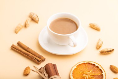 Bademli kompozisyon, tarçın ve turuncu pastel arka planda bir fincan kahve. Boş, yan görüş, durgun hayat, yakın çekim..