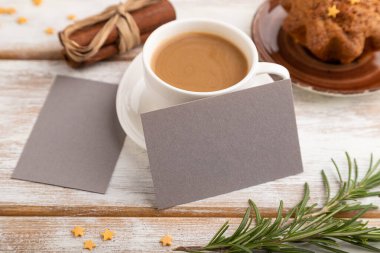 Gri kağıt kartvizit modeli, beyaz ahşap arka planda bir fincan kahve ve kek. Boş, yan görüş, durgun hayat..