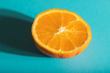 Olgun, mavi pastel arka planda turuncu kesilmiş. Yan görüş, yakın çekim, sert ışık. Tropik, sağlıklı gıda, konsept, minimalizm.