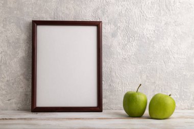 Kahverengi ahşap çerçeve modeli ve gri beton arka planda yeşil elma. Boş, dikey yönelim, natürmort yaşam, kopyalama alanı.