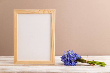 Bahar kar tanesi çiçekli ahşap çerçeve bej renkli pastel arka planda BlueBell. Yan görünüm, kopyalama alanı, natürmort, model, şablon, bahar minimalizmi kavramı.