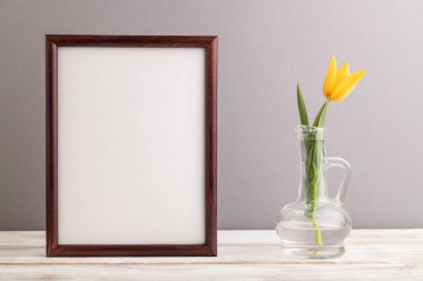 Gri pastel arka planda turuncu lale çiçekli ahşap çerçeve. Yan görünüm, kopyalama alanı, natürmort, model, şablon, bahar, yaz minimalizmi kavramı.