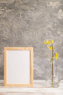 Sarı alabalık zambaklı ahşap çerçeve ya da gri beton arka planda cam camlı köpek dişli mor çiçekler. Yan görünüm, kopyalama alanı, modelleme, şablon, bahar, yaz minimalizmi kavramı.