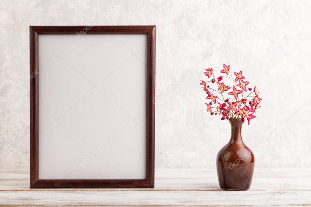 Wooden frame with purple barrenwort flowers in ceramic vase on gray concrete background. side view, copy space, still life, mockup, template, spring, summer minimalism concept.