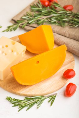 Beyaz ahşap arka plan ve keten tekstil üzerinde biberiyeli ve domatesli çeşitli peynir çeşitleri. Yan görünüm, kapat, kapat, seçici odaklanma.