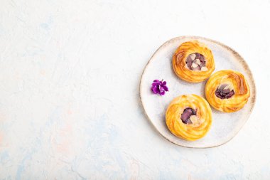 Reçelli küçük peynirli kekler ve beyaz beton arka planda bir fincan kahveyle badem. Üst görünüm, düz görünüm, kopyalama alanı.