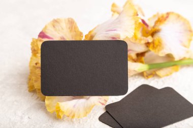 Beyaz beton arka planda sarı çiçekli siyah kartvizit. Yan görünüm, kopyalama alanı, modelleme, şablon, bahar, yaz minimalizmi kavramı.