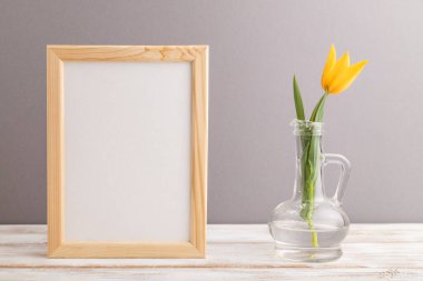 Gri pastel arka planda turuncu lale çiçekli ahşap çerçeve. Yan görünüm, kopyalama alanı, natürmort, model, şablon, bahar, yaz minimalizmi kavramı.