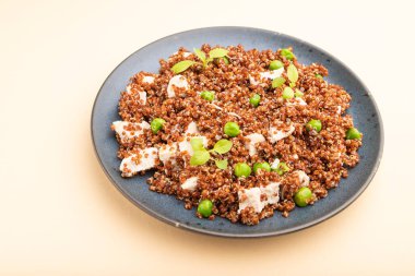 Yeşil bezelyeli kinoa lapası ve turuncu arkaplanda seramik tabakta tavuk. Yan görünüm, kapat.