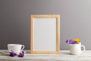 Bej rengi ahşap çerçeve modeli, kar damlası çiçekleri ve gri kağıttan arka planda beyaz kahve fincanı. Boş, dikey yönelim, natürmort yaşam, kopyalama alanı.