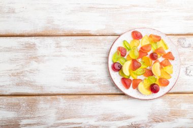 Beyaz ahşap arka planda çeşitli meyve jöleli şekerler. Üst görünüm, düz görünüm, kopyalama alanı.