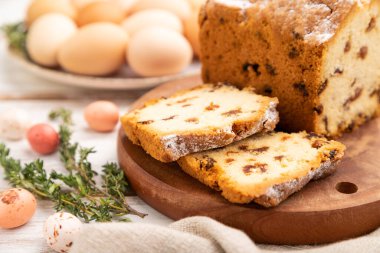 Beyaz ahşap arka planda kuru üzümlü ve yumurtalı ev yapımı paskalya pastası ve keten tekstil. Yan görünüm, yakın görünüm, seçici odak.