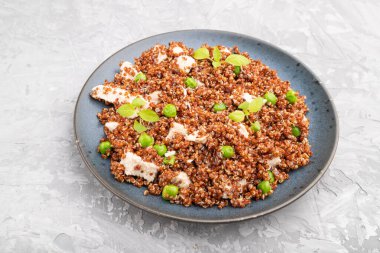 Yeşil bezelyeli kinoa lapası ve gri beton arka planda seramik tabakta tavuk. Yan görünüm, kapat.