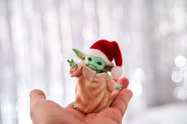 Dec, 2020: Мбаппе из Baby Yoda, экшн-фигура, стоящая в красной шапке на заднем плане. Эффект Боке. 