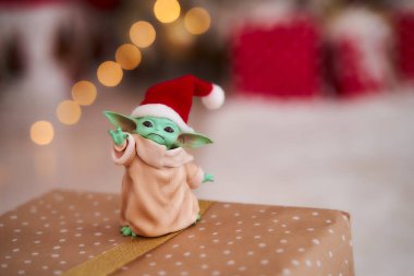 Aralık 2020: Bebek Yoda 'nın görüntüsü, bir aksiyon figürü, Noel arkaplanında kırmızı başlık takıyor. Bokeh etkisi. 