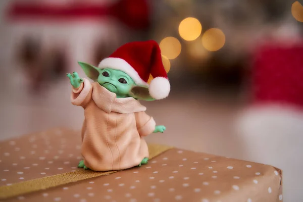 Aralık 2020: Bebek Yoda 'nın görüntüsü, bir aksiyon figürü, Noel arkaplanında kırmızı başlık takıyor. Bokeh etkisi. 