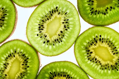 Beyaz arka planda bir sürü kivi var. İçinde tohumlar ve makro manzarayla ikiye bölünmüş Kivi meyvesi..