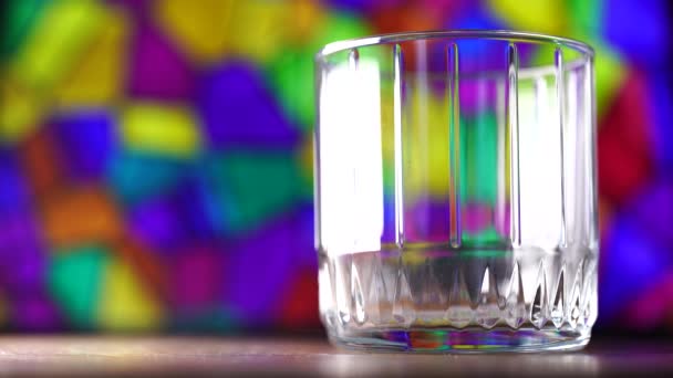 Χρωματιστά ξύλινα ραβδιά πέφτουν σε ένα ποτήρι. Πολύχρωμο φόντο. — Αρχείο Βίντεο