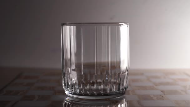 Een prachtig glas waarin sinaasappelsap wordt gegoten. Lichte achtergrond — Stockvideo