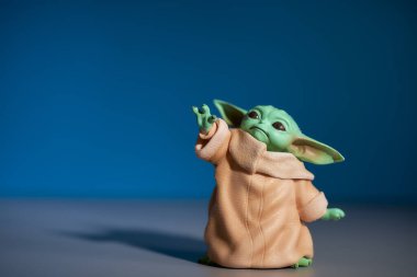 Mart 2021: Bebek Yoda 'nın görüntüsü, bir aksiyon figürü, gri ve mavi arka planda duruyor. Yüksek kalite fotoğraf