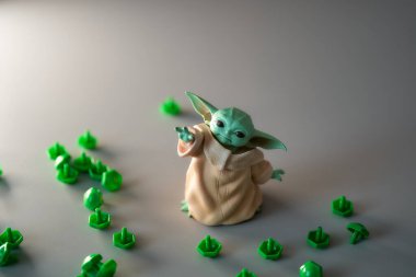 2021 Mart 'ında, oyuncak bebek Yoda' nın görüntüsü gri arka plandaki plastik düğmeler arasında yer aldı. Gri arka plan. Yüksek kalite fotoğraf