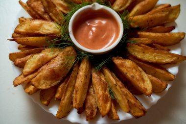 Dilimlenmiş patatesler beyaz bir tabakta yatıyor. Ketçaplı sos. Yüksek kalite fotoğraf