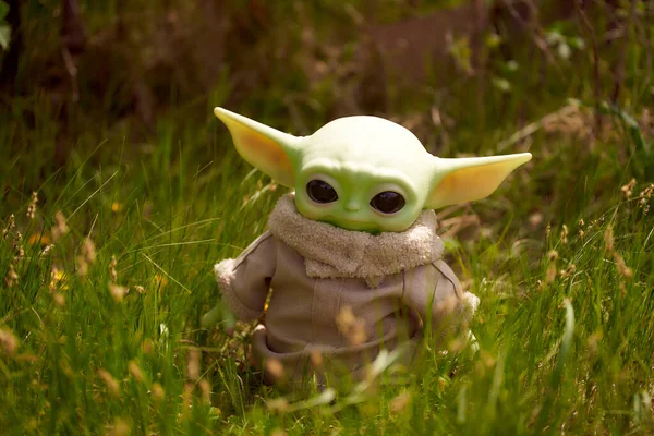 Junio, 2021: Baby Yoda, una figura de acción de Star Wars parada en la hierba verde —  Fotos de Stock