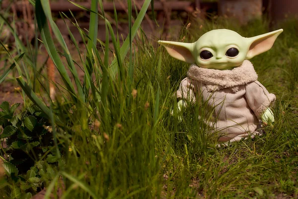 Junio, 2021: Baby Yoda, una figura de acción de Star Wars parada en la hierba verde —  Fotos de Stock